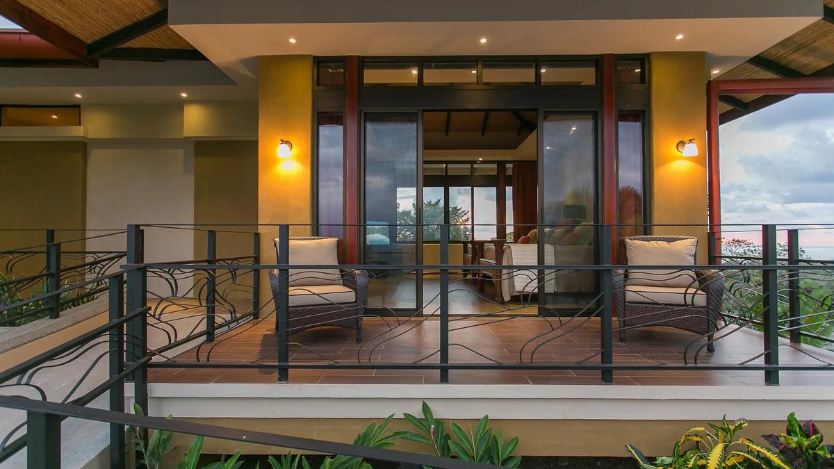 Wicker armchairs on the balcony at dusk outside the Casa Anaka master suite