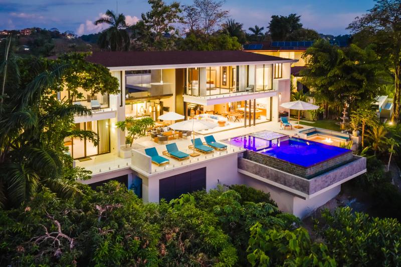 Casa Nola at dusk, glass walls glowing above the lit infinity pool