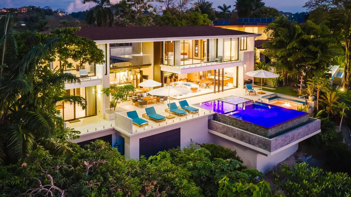 Casa Nola at dusk, glass walls glowing above the lit infinity pool