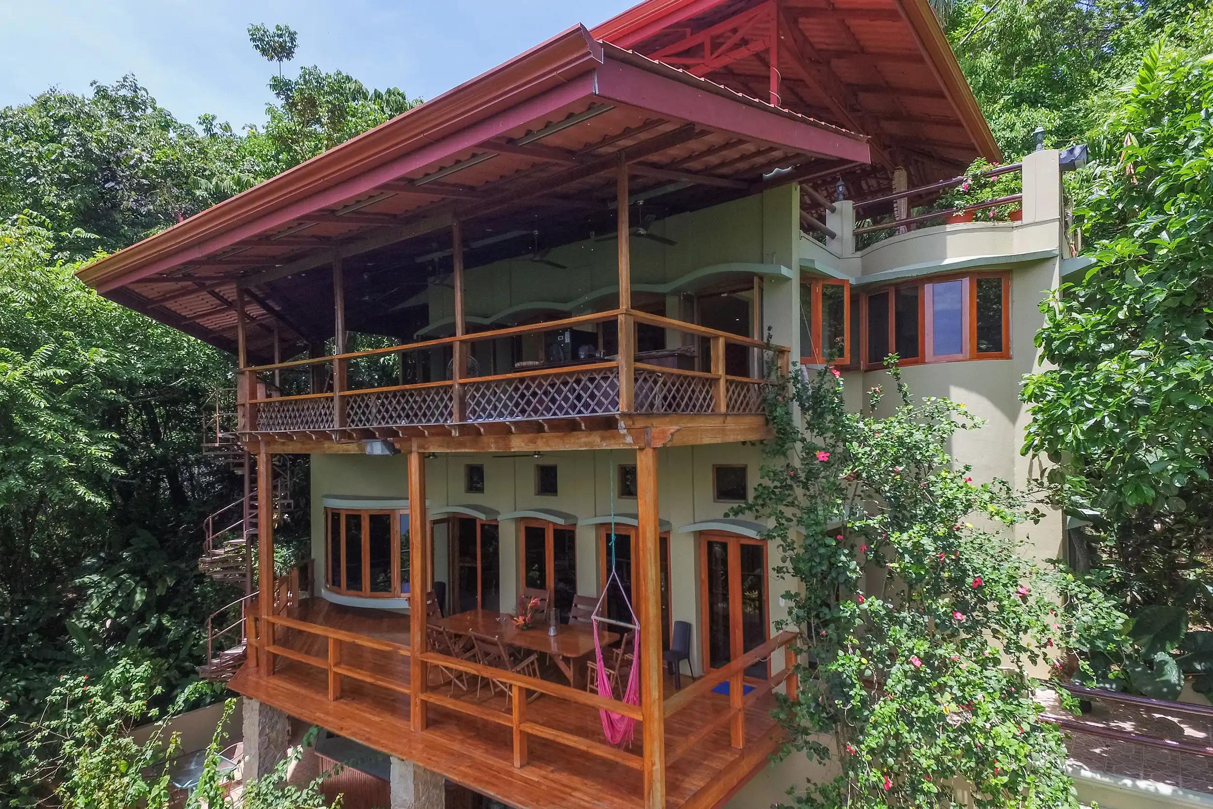 Casa Pura Paz exterior with wraparound balconies, hammock, and flowering hibiscus