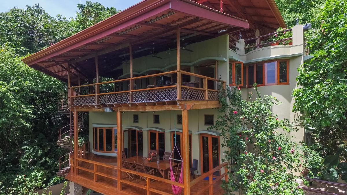 Casa Pura Paz exterior with wraparound balconies, hammock, and flowering hibiscus