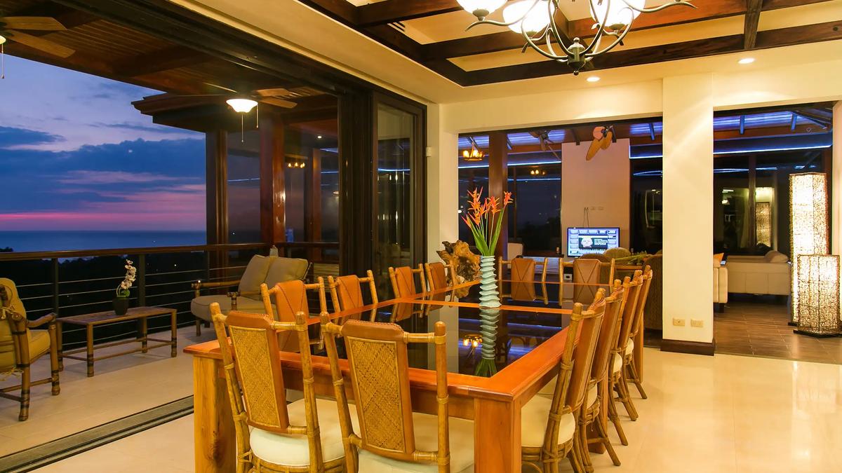 Glass-top dining table for ten at Villa Celaje with a sunset ocean view off the balcony