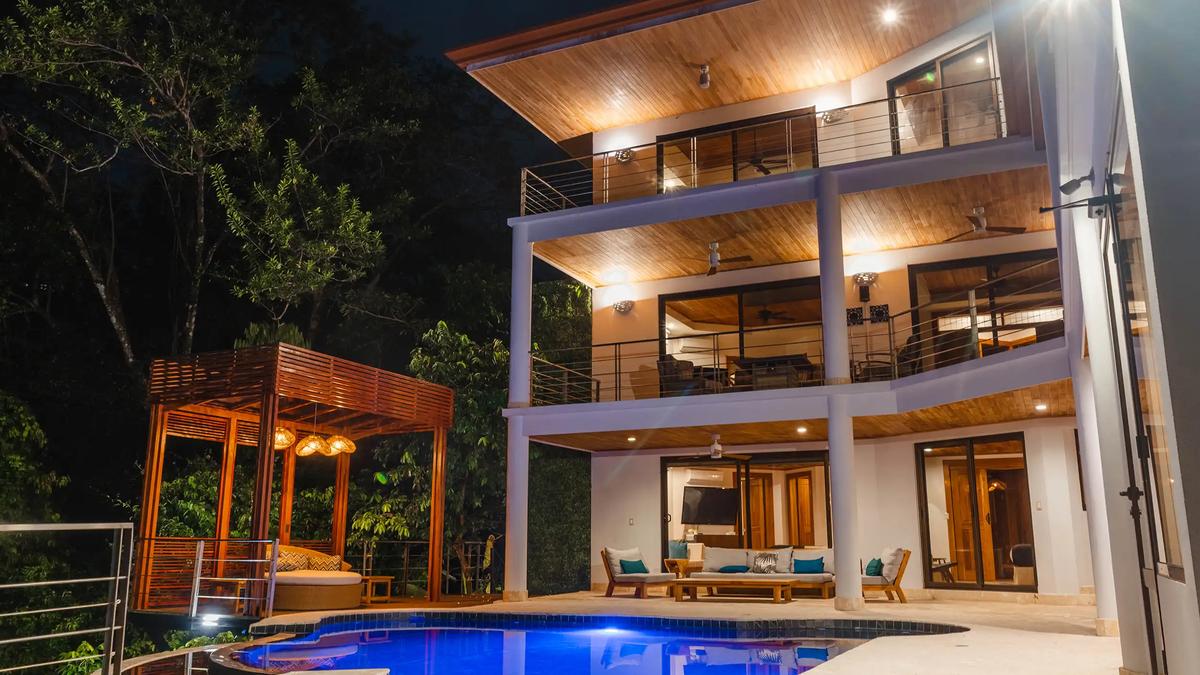 Three stories of Casa Anjali and its blue-lit pool glowing at night