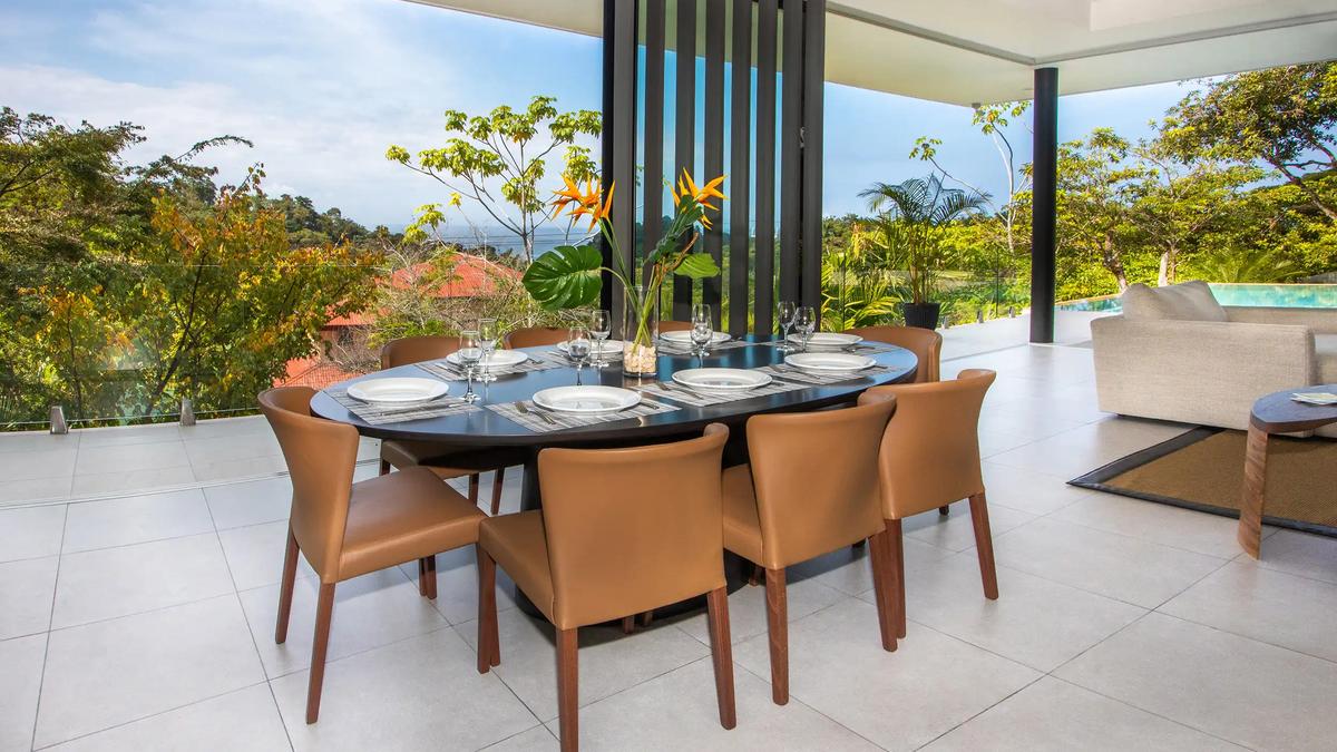 Dining table set for eight at Casa Nueva Vida with treetop and ocean views