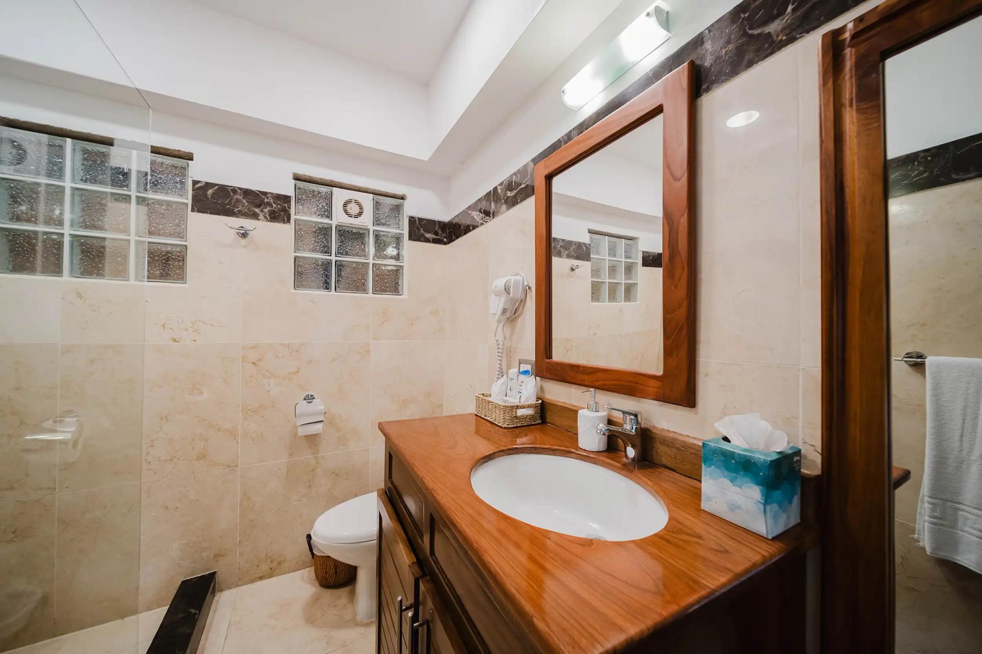 Bathroom at Casa Grande Vista with wood vanity and marble tile walls