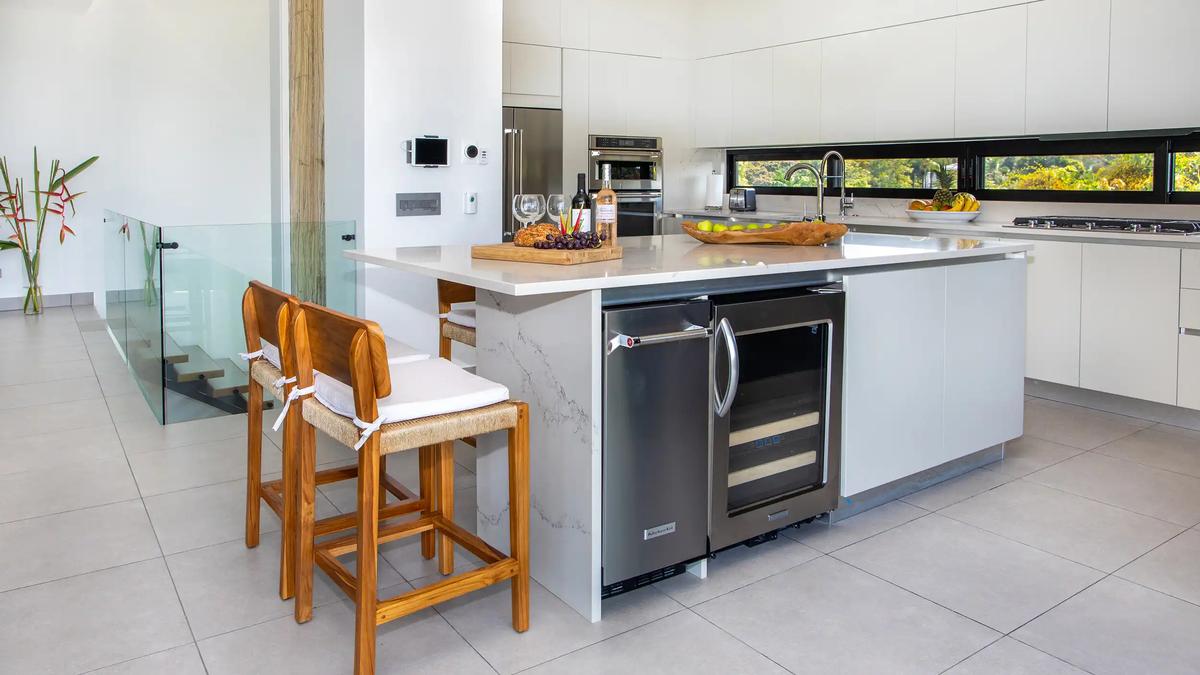 Casa Nueva Vida kitchen island with wine cooler, stainless appliances, and glass stair rail