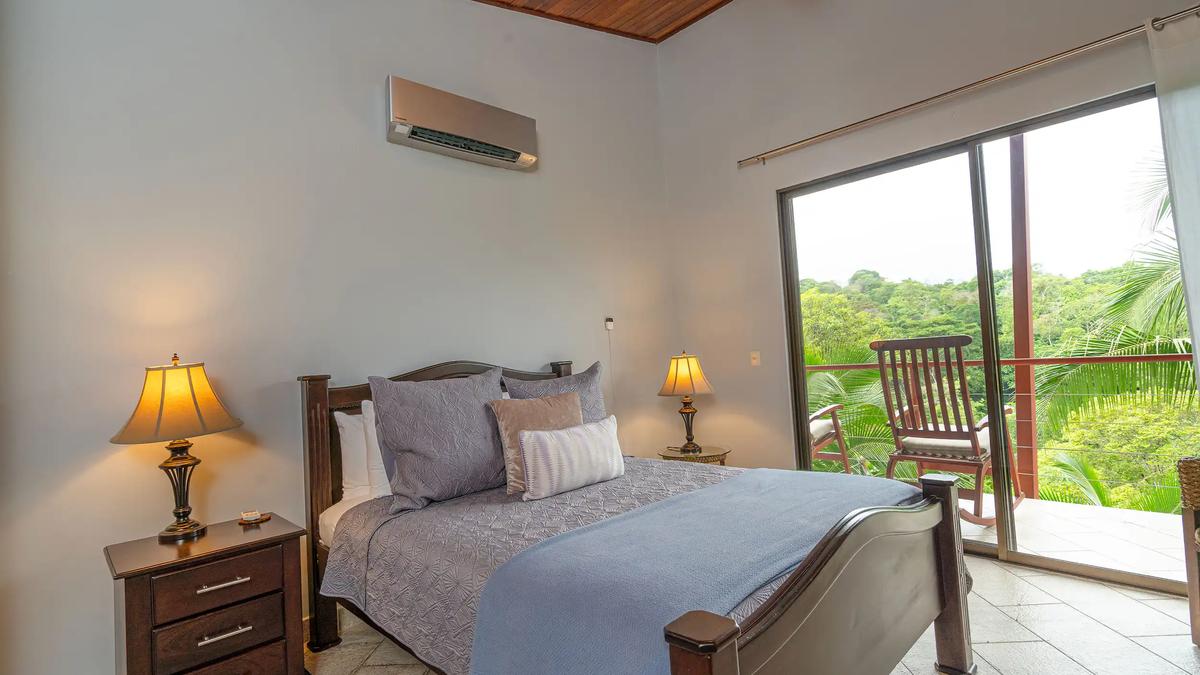 Casa Serenidad bedroom opening to a balcony with rocking chairs and jungle views