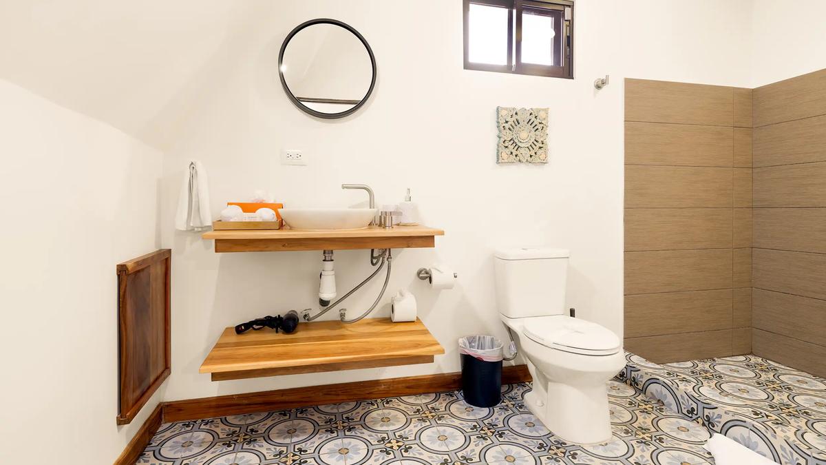 Casa Vista Verde bathroom with floating wood vanity, round mirror, and patterned tile floor
