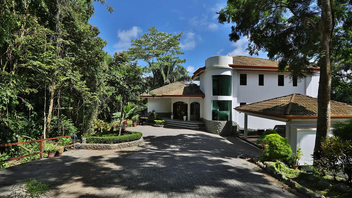 Paver driveway curving up to Casa Anjali's white facade under shade trees