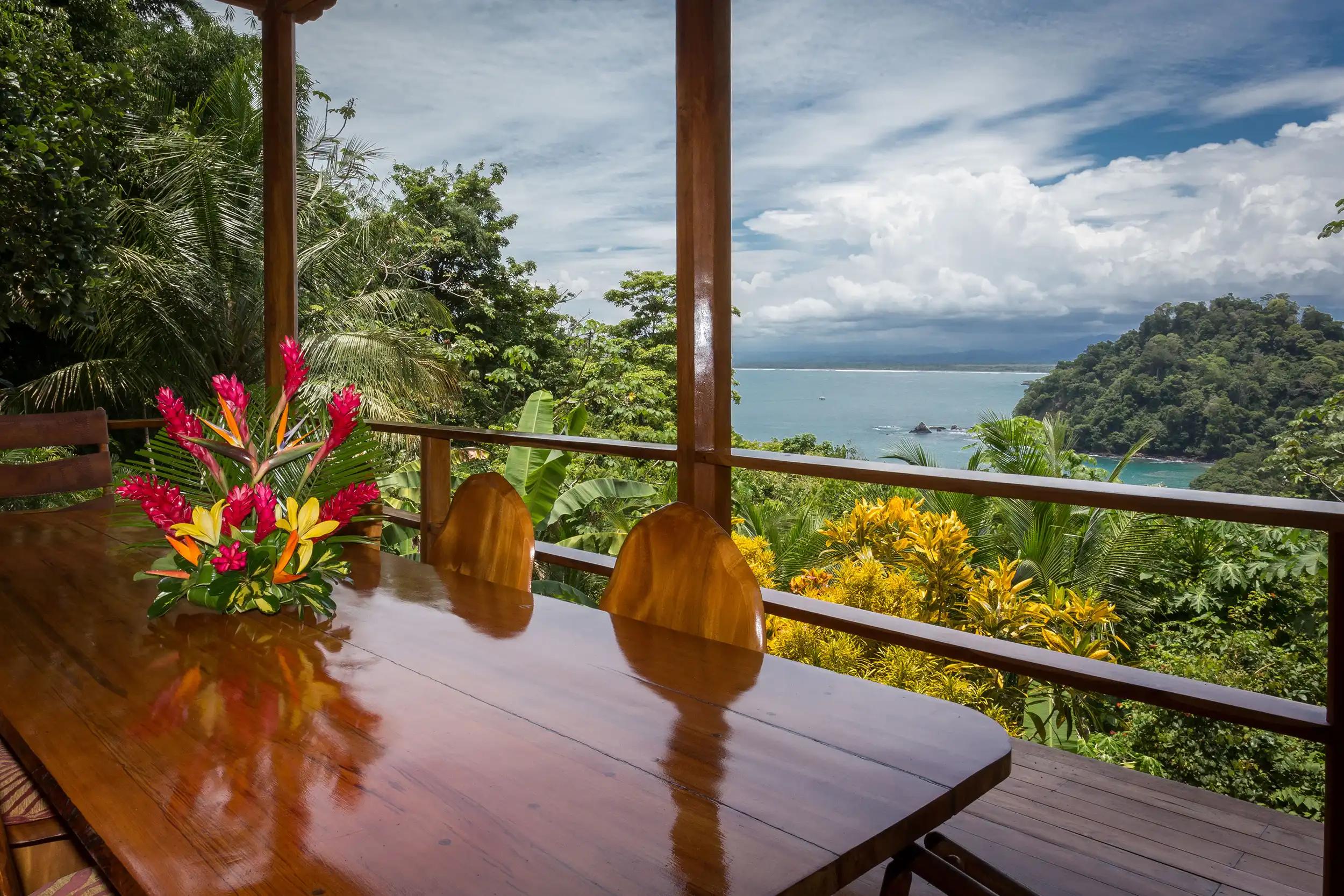 Outdoor dining table at Casa Pura Paz with tropical flowers and Pacific Ocean view