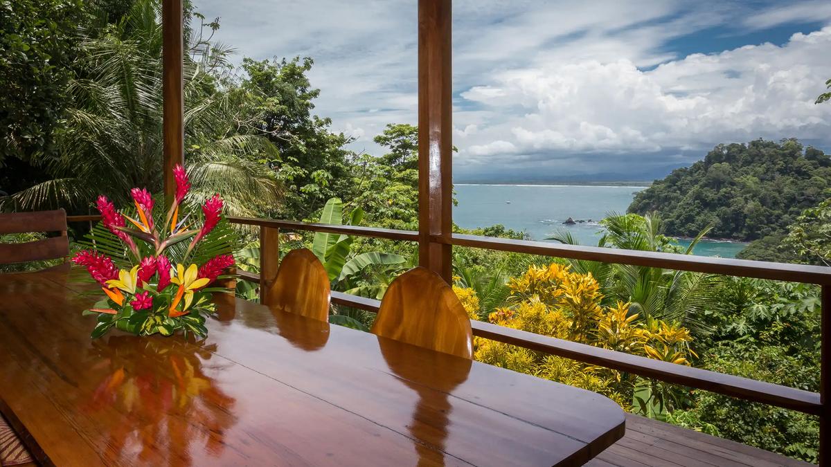 Outdoor dining table at Casa Pura Paz with tropical flowers and Pacific Ocean view