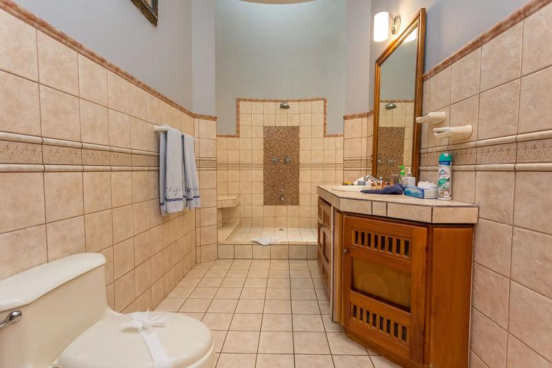 Tiled bathroom at Casa Pura Paz with walk in shower and carved wood vanity