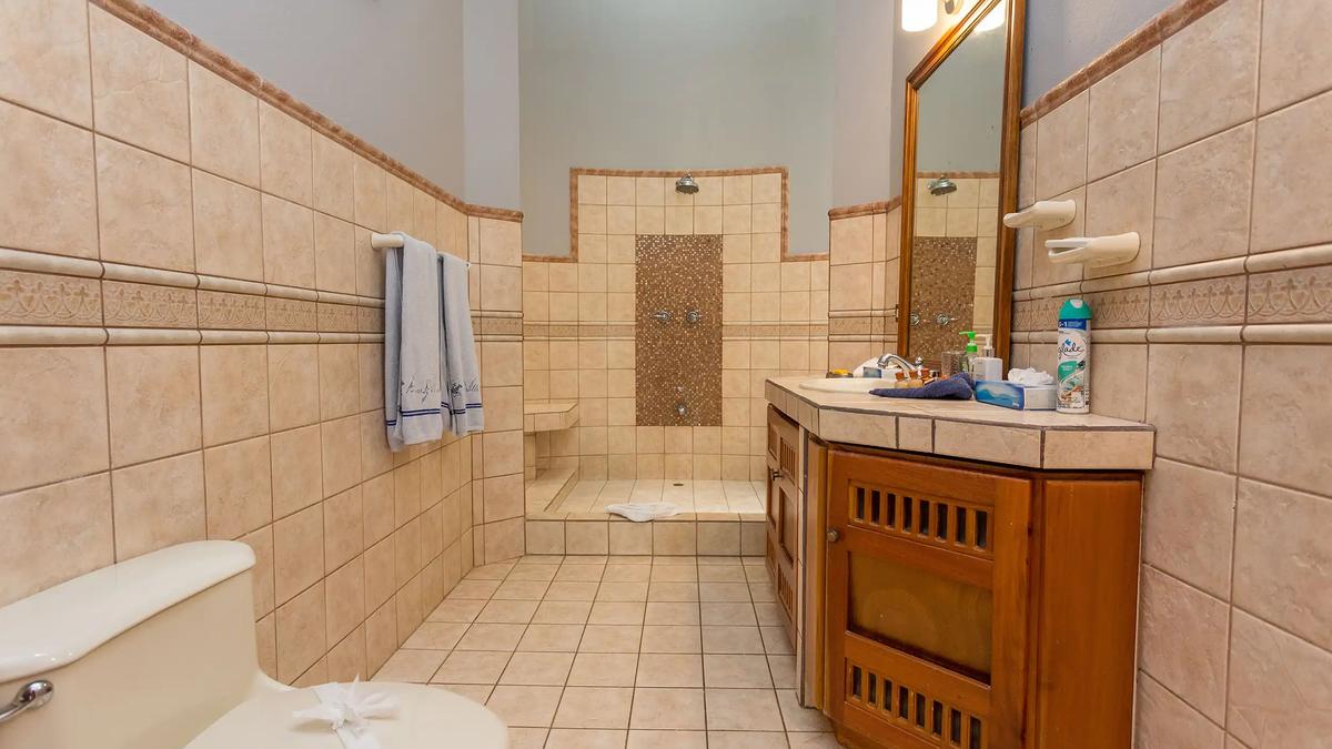 Tiled bathroom at Casa Pura Paz with walk in shower and carved wood vanity