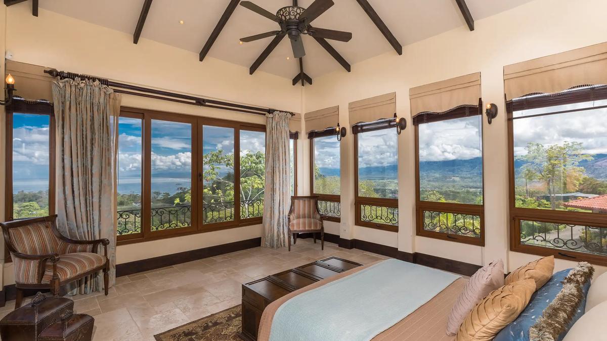 Bedroom at Villa Marbella ringed by windows with ocean and mountain views