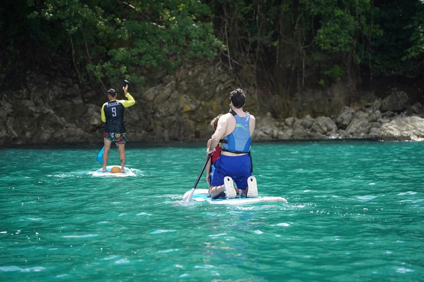 Two paddleboarders in a calm cove on the Manuel Antonio coast