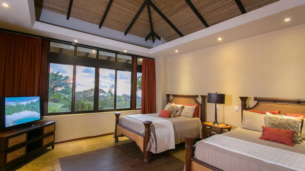 Bedroom with two queen beds under a vaulted bamboo ceiling at Casa Anaka