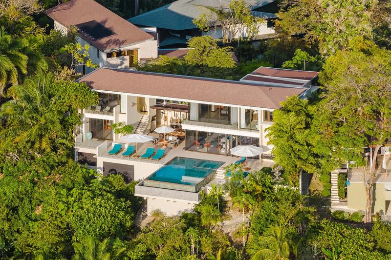 Aerial view of Casa Nola's infinity pool, sun deck, and terraces tucked into rainforest