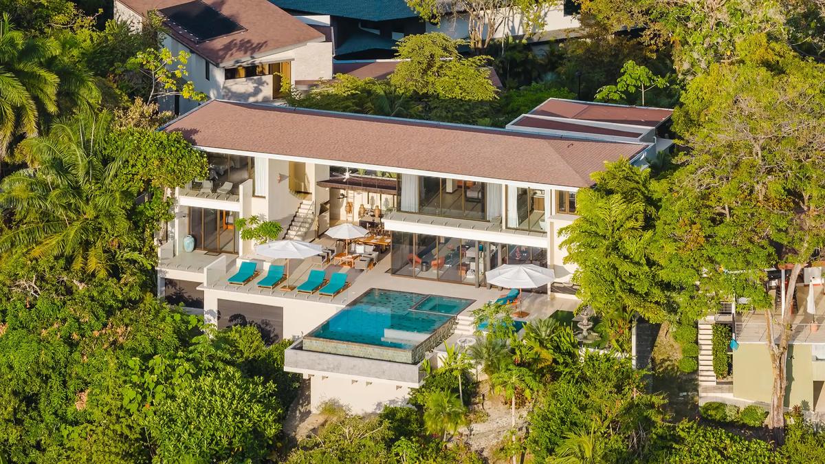 Aerial view of Casa Nola's infinity pool, sun deck, and terraces tucked into rainforest