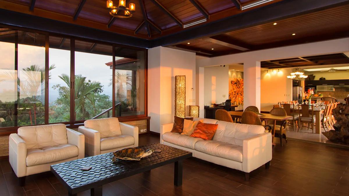 Villa Celaje's living room with white leather seating, carved coffee table, and rainforest windows