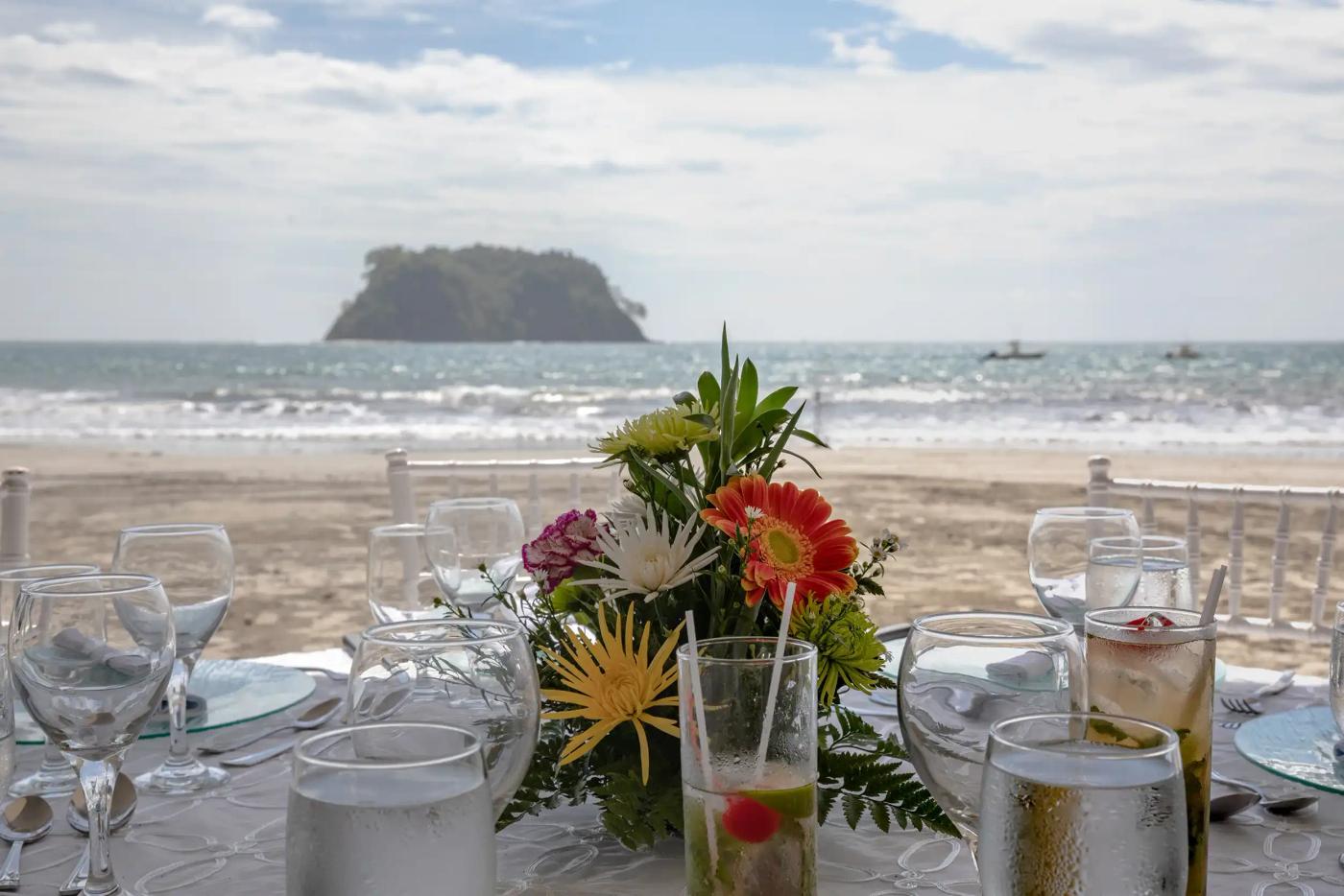 Table set with tropical flowers and glassware on the beach at Manuel Antonio