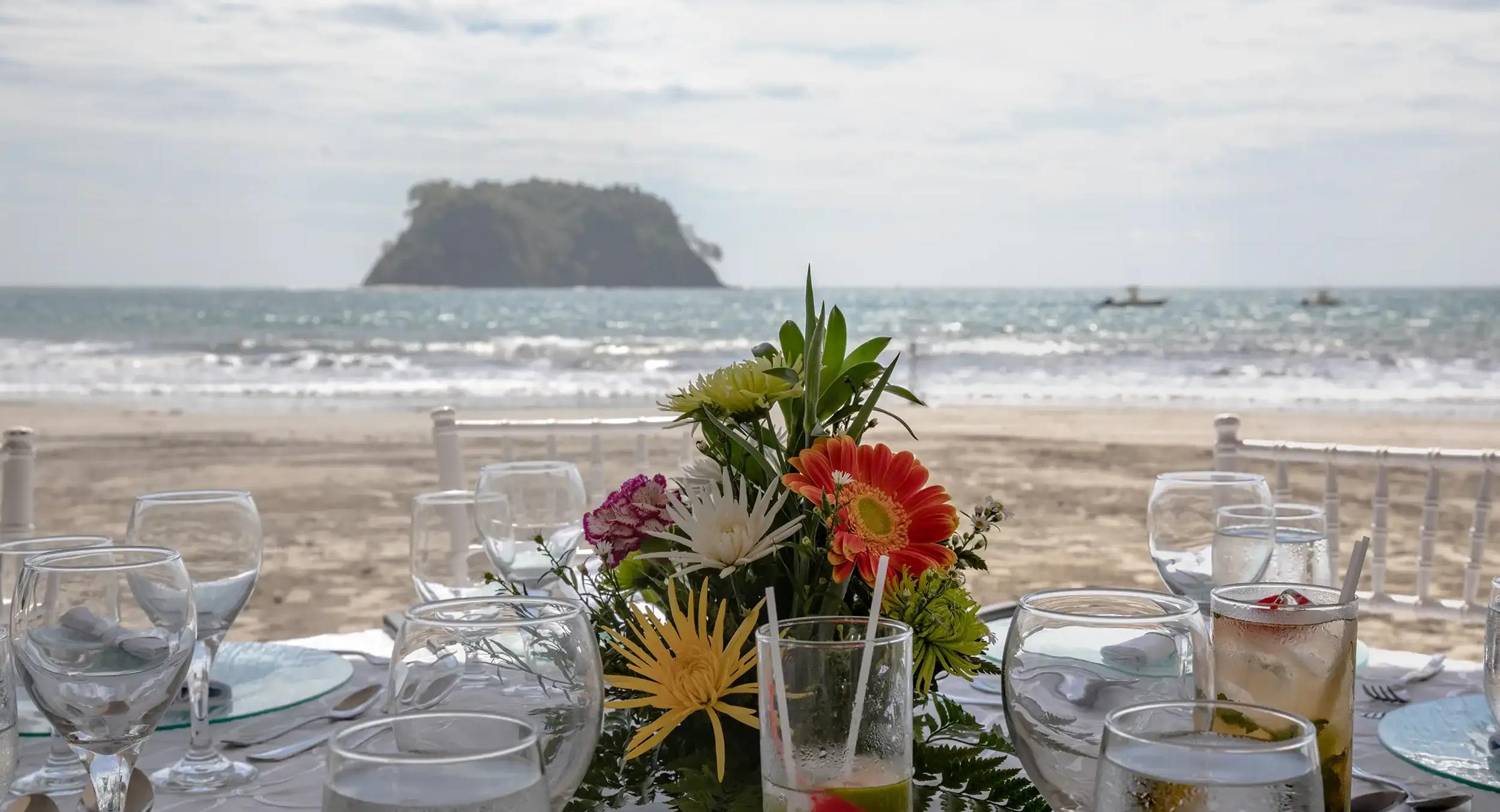 Table set with tropical flowers and glassware on the beach at Manuel Antonio