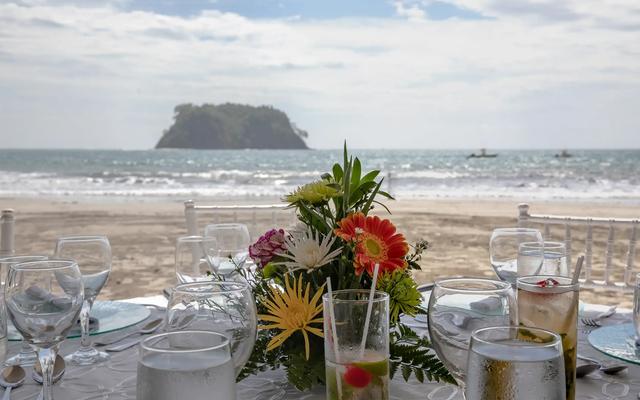 Table set with tropical flowers and glassware on the beach at Manuel Antonio