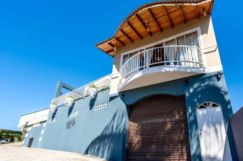 Blue street facade with curved balcony and garage entrance at Casa Alta Vista