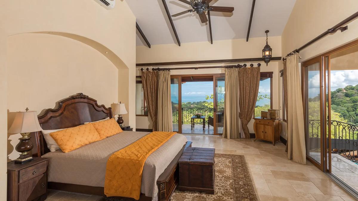 Villa Marbella bedroom with carved headboard and sliding doors to an ocean view balcony