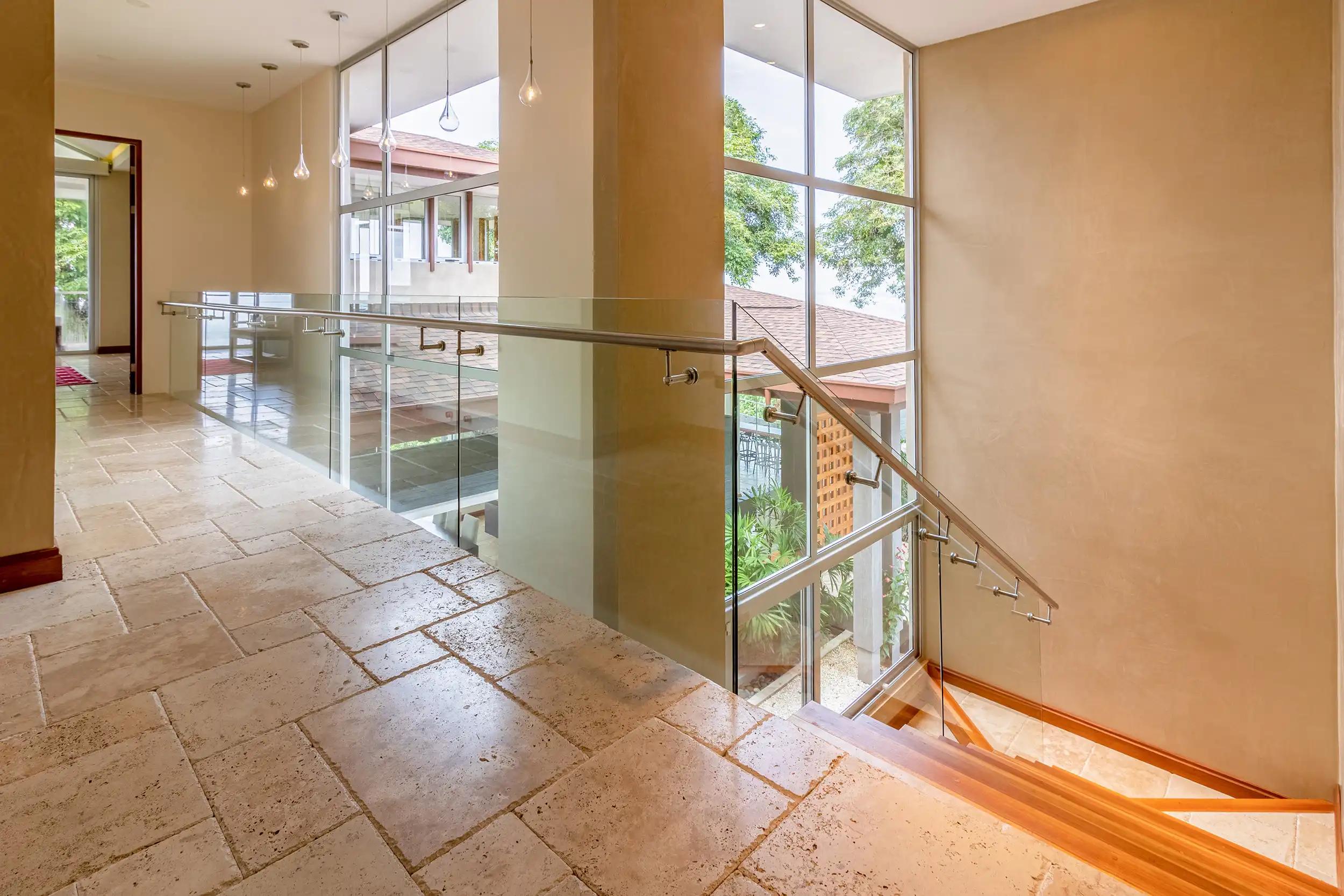 Upstairs hallway at Casa Contee with glass railings and teardrop pendant lights