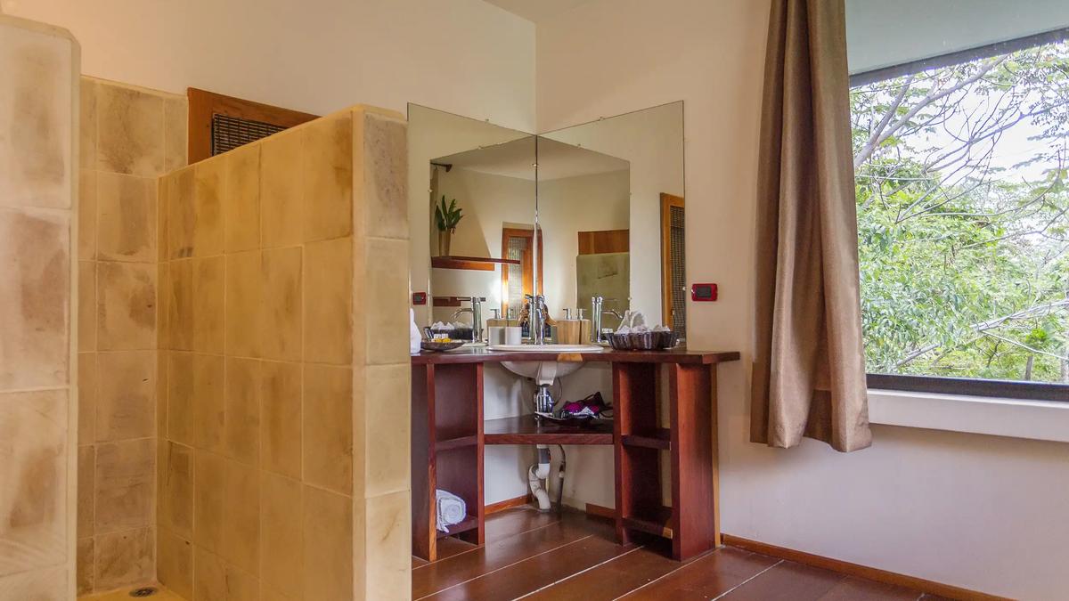 Stone tiled walk-in shower and corner wood vanity in a Casa Luz bathroom
