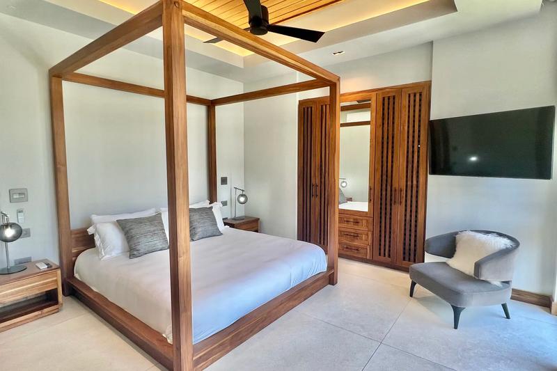 Guest bedroom at Villa de Grace with canopy bed, wood wardrobe, and armchair