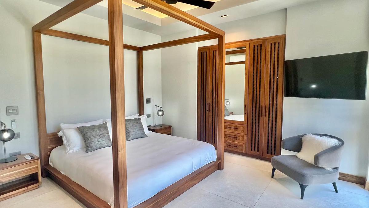 Guest bedroom at Villa de Grace with canopy bed, wood wardrobe, and armchair