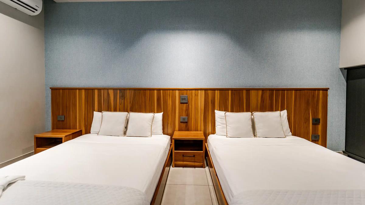 Two beds sharing a full teak headboard wall at Casa Blue Marlin