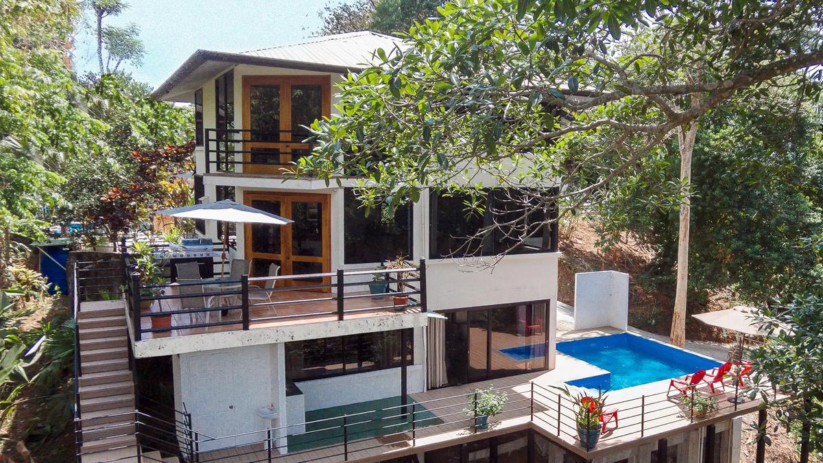 Casa Luz exterior showing three levels, terraces and blue pool amid rainforest
