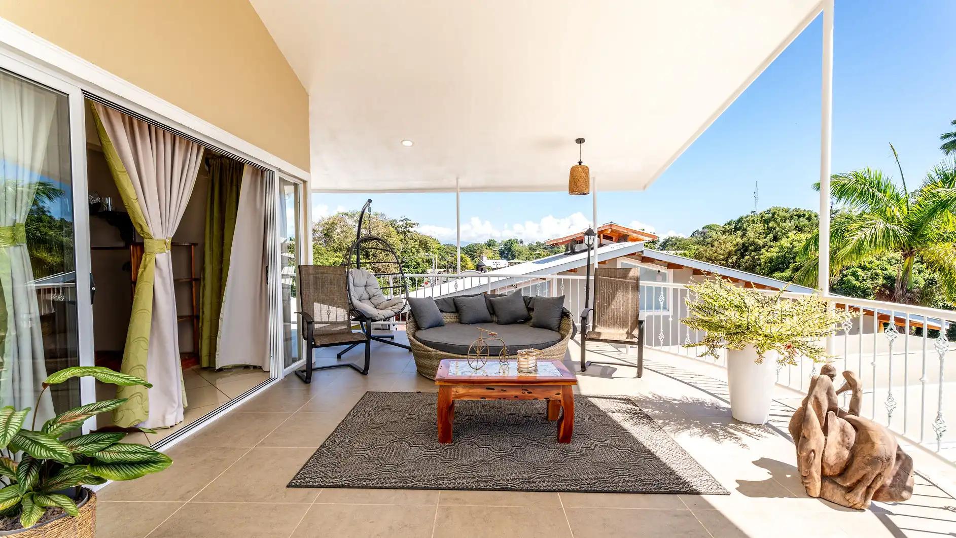 Covered terrace lounge with daybed and hanging egg chair at Casa Alta Vista