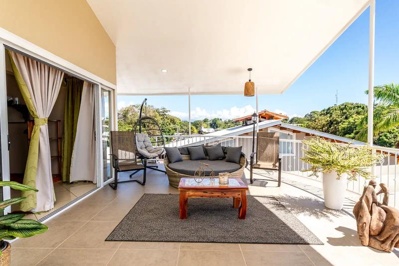 Covered terrace lounge with daybed and hanging egg chair at Casa Alta Vista