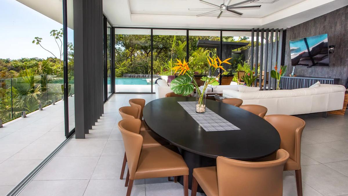 Oval dining table with leather chairs at Casa Nueva Vida looking out to the pool