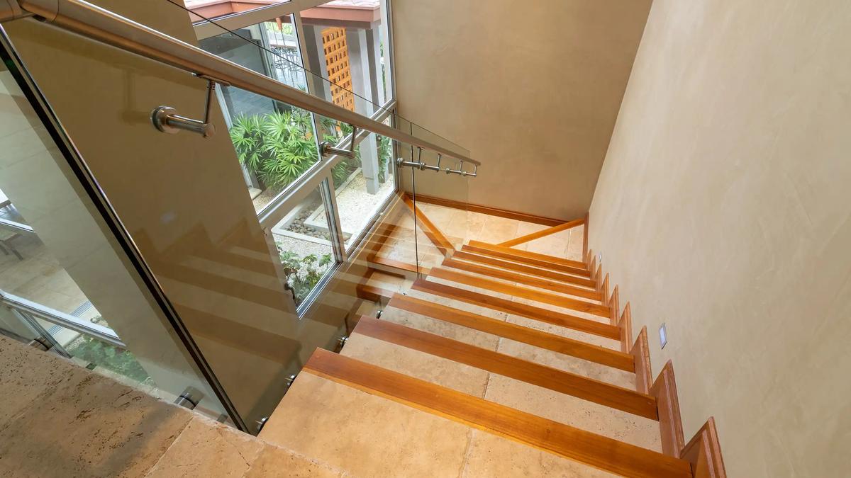 Wooden staircase with glass railing and garden window inside Casa Contee