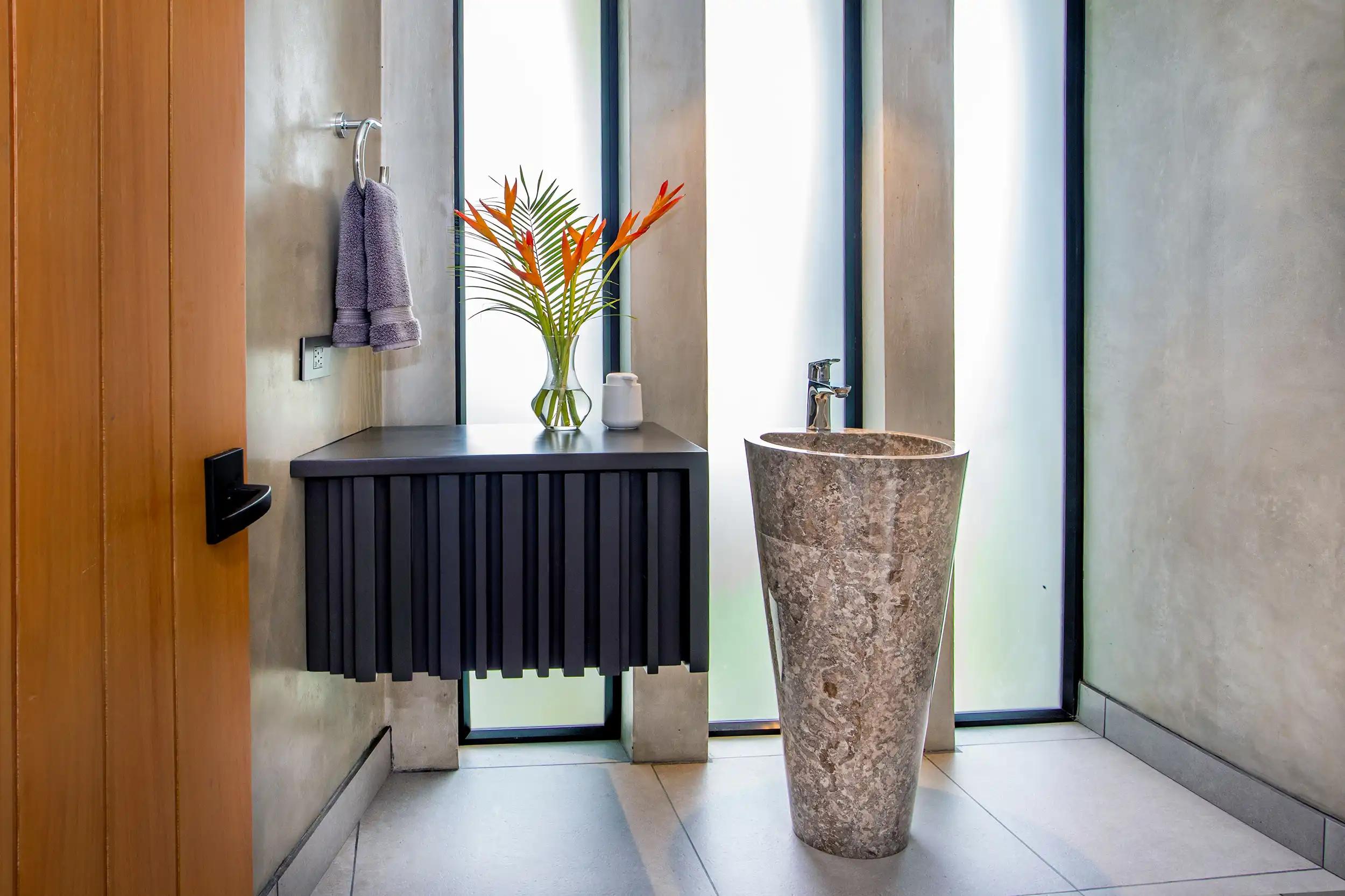 Powder room at Casa Nueva Vida with stone pedestal sink and floating black vanity