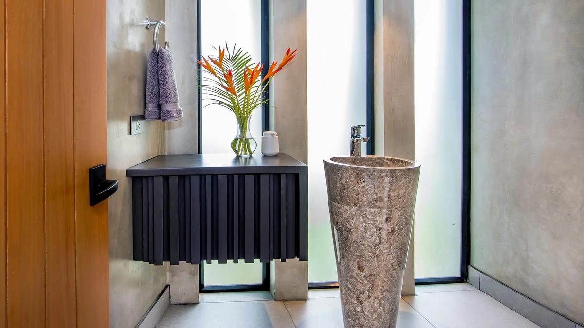 Powder room at Casa Nueva Vida with stone pedestal sink and floating black vanity