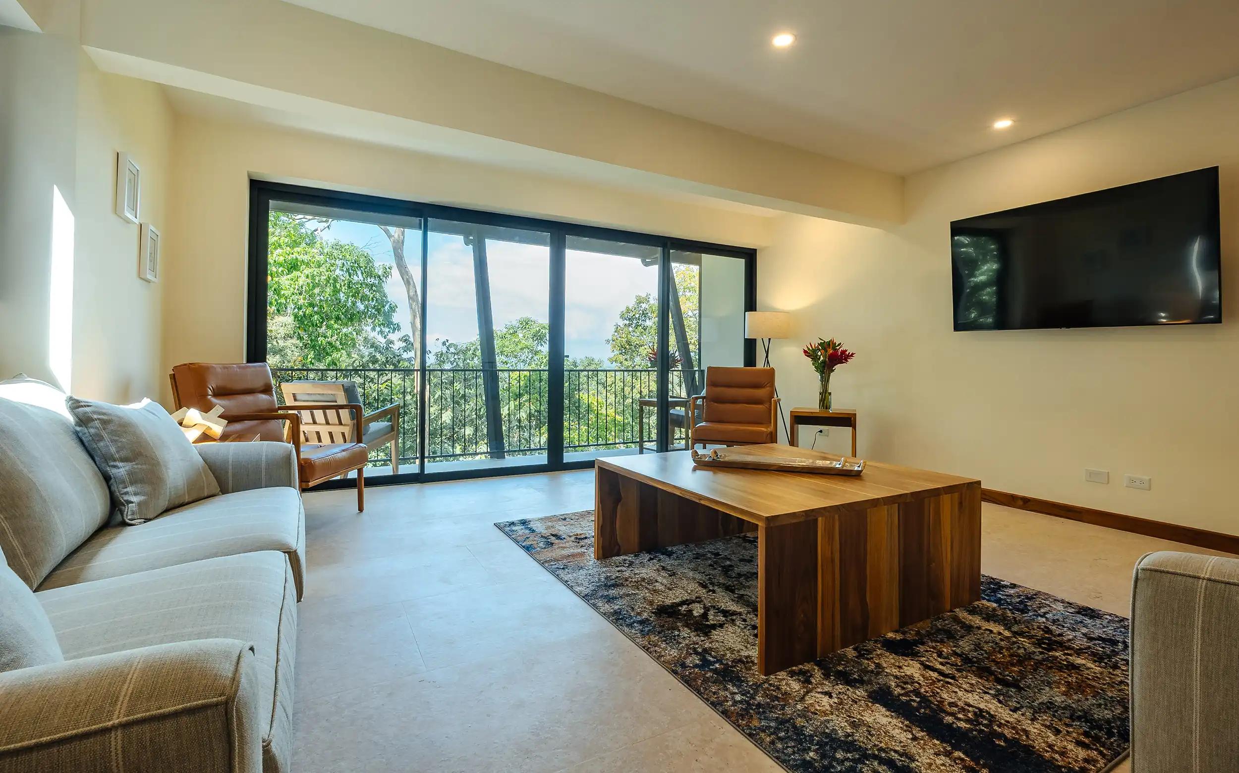 Casa Rambutan living area with gray sofas, wood coffee table, and balcony sliding doors