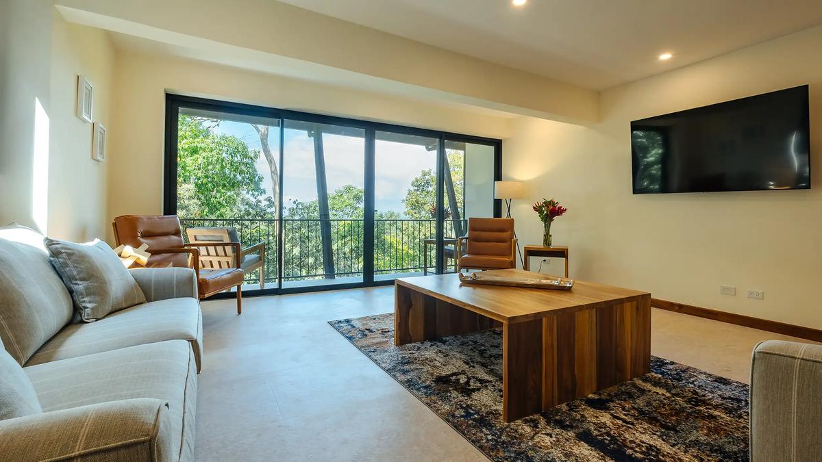 Casa Rambutan living area with gray sofas, wood coffee table, and balcony sliding doors