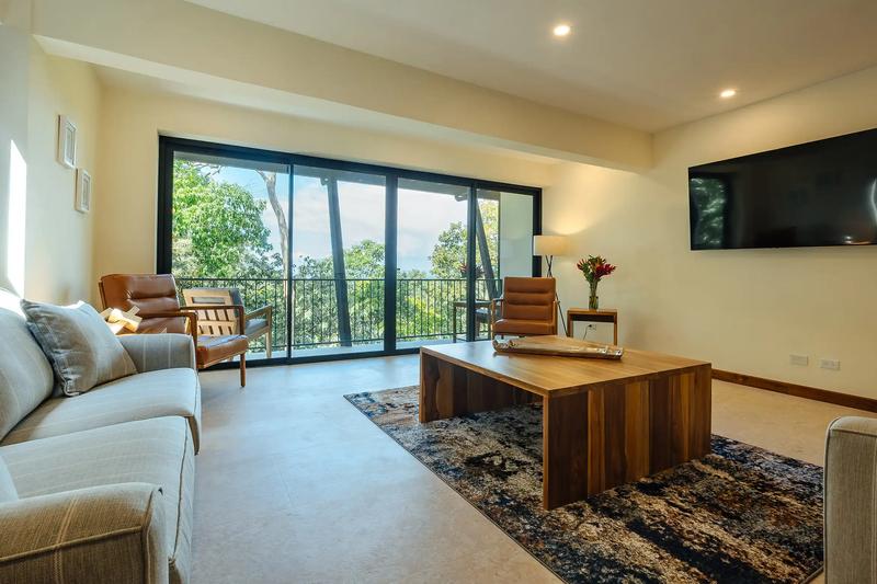 Casa Rambutan living area with gray sofas, wood coffee table, and balcony sliding doors