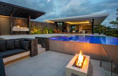 Casa Nueva Vida at dusk with lit pool, fire pit, and covered outdoor kitchen