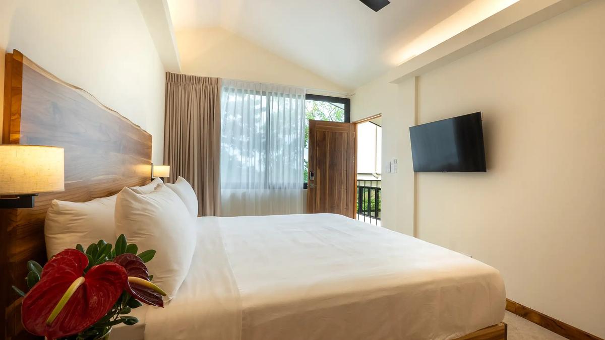 Casa Rambutan bedroom with wall mounted TV and door opening to the balcony