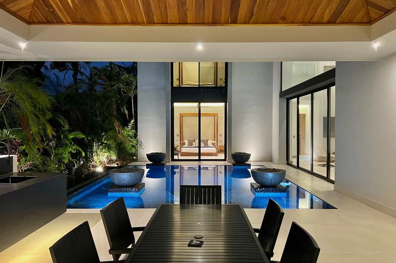 Evening view across the pool and fire bowls to a bedroom at Villa de Grace