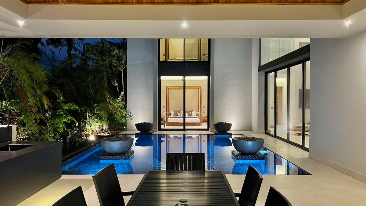 Evening view across the pool and fire bowls to a bedroom at Villa de Grace