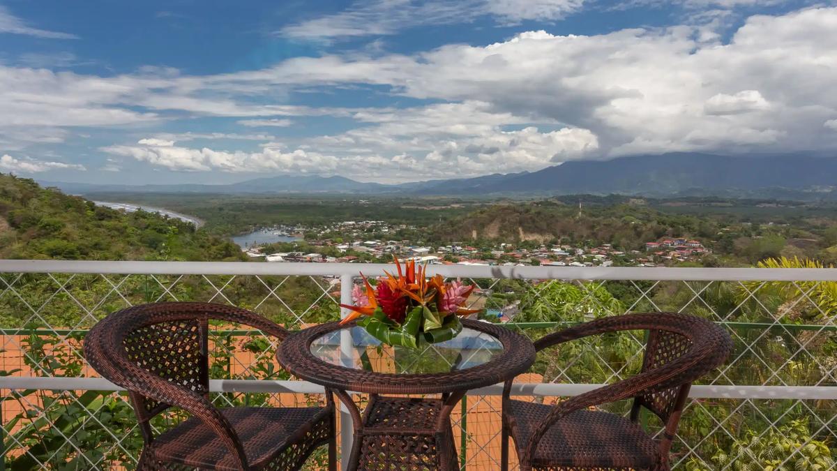 Wicker bistro table on the Casa Moreno balcony overlooking Quepos and the coastline