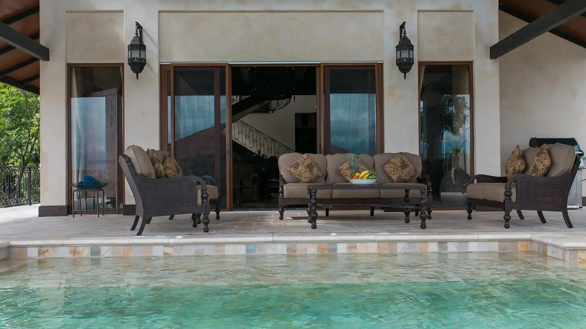 Poolside terrace at Villa Marbella with cushioned seating and lantern sconces