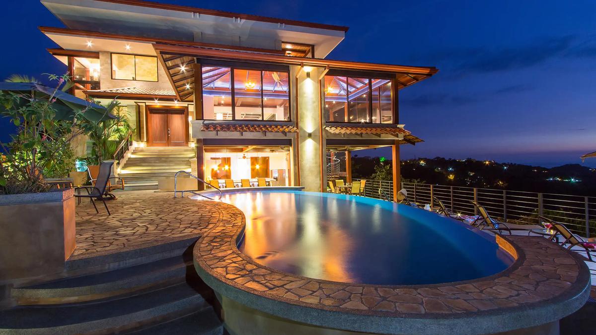 Twilight view of Villa Celaje's infinity pool and glowing multilevel facade